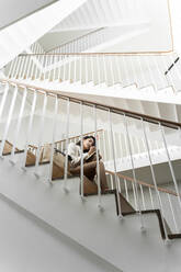 Young woman sitting on stairs taking notes - AFVF05323