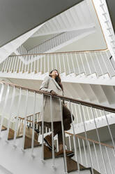 Young woman walking down stairs in staircase - AFVF05324