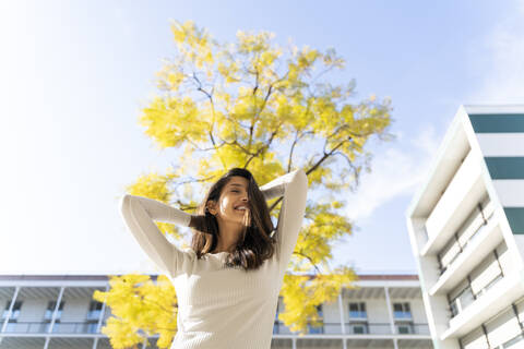 Glückliche junge Frau im Freien vor einem Baum, lizenzfreies Stockfoto