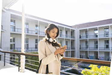 Young woman using smartphone on balcony - AFVF05363