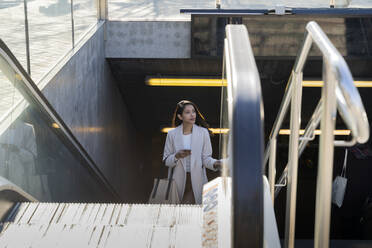 Young woman with smartphone leaving subway station - AFVF05382