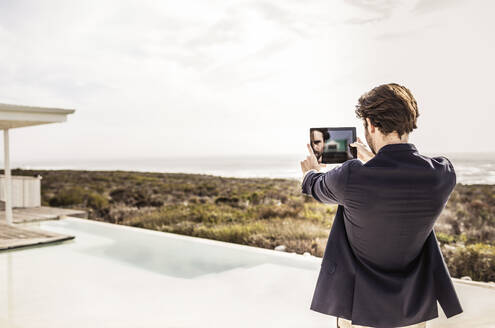 Junger Mann in Business-Jacke macht ein Selfie in einem Strandhaus mit Pool - SDAHF00153