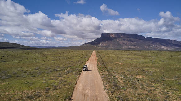 Südafrika, Western Cape, Blanco, Luftaufnahme eines weißen Geländewagens, der auf einem Feldweg in Richtung Berge fährt - VEGF01549