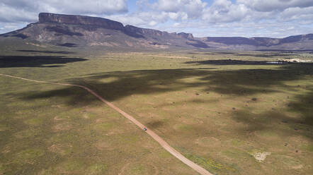 Südafrika, Western Cape, Blanco, Luftaufnahme eines weißen Geländewagens, der auf einem Feldweg in Richtung Berge fährt - VEGF01552