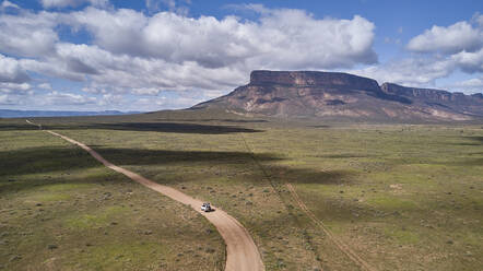 Südafrika, Western Cape, Blanco, Luftaufnahme eines weißen Geländewagens, der auf einem Feldweg in Richtung Berge fährt - VEGF01553