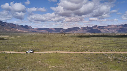 Südafrika, Western Cape, Blanco, Luftaufnahme eines weißen Geländewagens, der auf einem Feldweg in Richtung Berge fährt - VEGF01554