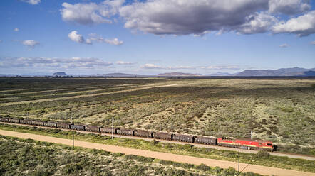 South Africa, Western Cape, Aerial view of cargo train passing by fields - VEGF01561