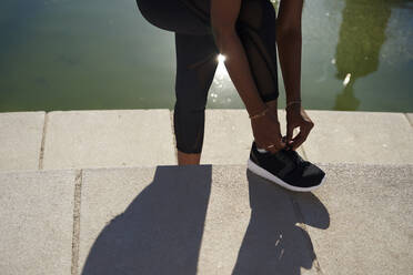 Woman tying shoelace of her black shoe - PACF00184