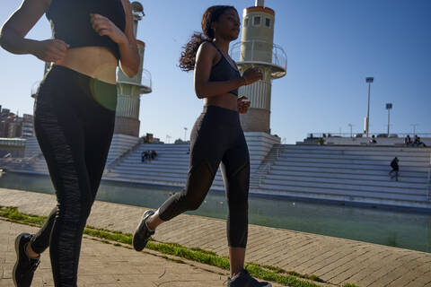 Zwei Sportlerinnen joggen an einem See in der Stadt, Barcelona, Spanien, lizenzfreies Stockfoto