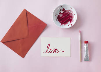 Making a Valetine's day card, red envelope and card with love written on it - MOMF00836