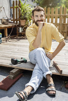 Junger Handwerker, der eine Pause vom Bau seiner Terrasse macht - PESF01769