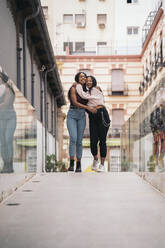 Zwei glückliche junge Frauen umarmen sich in der Stadt - MPPF00502