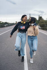 Zwei glückliche junge Frauen gehen auf einer Straße - MPPF00515