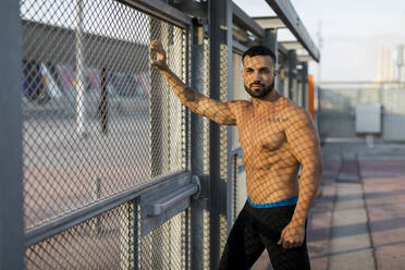 Sportsman leaning on a fence, looking at camera - MAUF03334