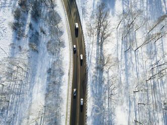 Russia, Saint Petersburg, Aerial view of cars driving along country road in winter - KNTF04346