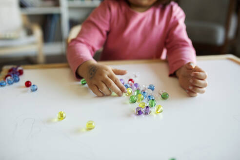 Crop-Ansicht von Mädchen spielen mit Murmeln auf dem Tisch - VABF02623