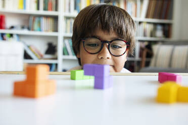 Porträt eines kleinen Jungen mit Brille, der zu Hause mit Bauklötzen spielt - VABF02641