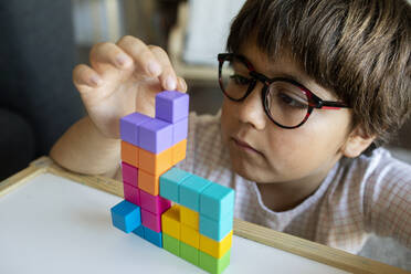 Portrait of little boy with glasses playing with building blocks - VABF02644