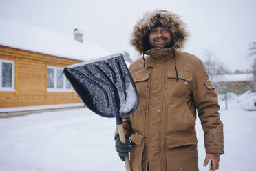 Porträt eines lächelnden Mannes mit Schneeschaufel - KNTF04408