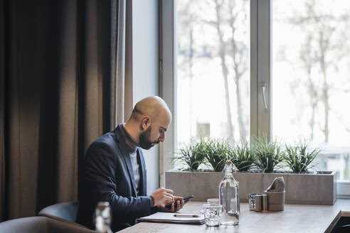 Businessman using smartphone in a cafe - AHSF01867