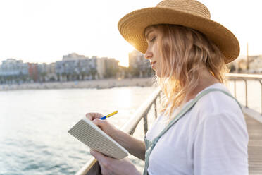 Junge Frau verbringt einen Tag am Meer und schreibt in ihr Tagebuch - AFVF05413