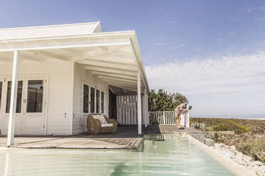 Man working on laptop next to pool at a beach house - SDAHF00163