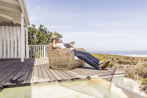Man fallen asleep while reading a book on a deck at the coast - SDAHF00166