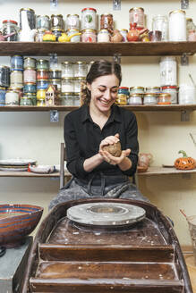 Smiling woman working on workpiece in pottery - VPIF02011