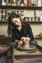 Smiling woman working on workpiece in pottery - VPIF02014