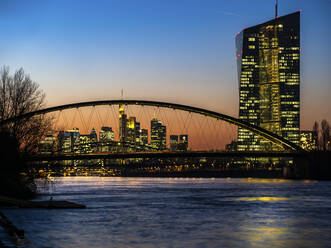 Deutschland, Hessen, Frankfurt, Skyline von Frankfurt am Main hinter der Ostendbrücke und der Europäischen Zentralbank in der Abenddämmerung - AMF07828