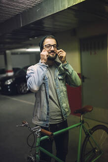 Young man standing in park house with his fixie bike - RAEF02333