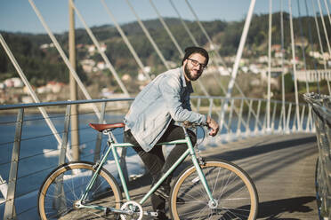 Junger Mann beim Pendeln in der Stadt mit seinem Fixie-Fahrrad - RAEF02349