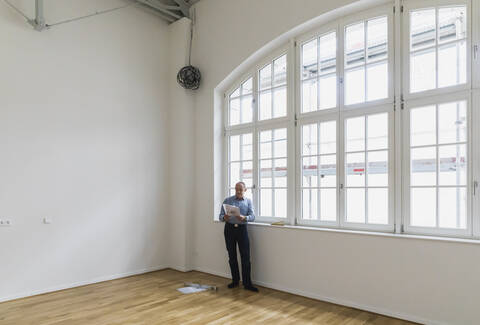 Mann prüft Spezifikationen eines renovierten Luxus-Lofts, lizenzfreies Stockfoto