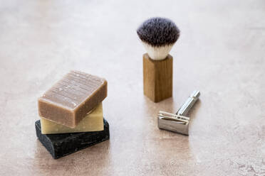 High angle close up of three bars of homemade bars of soap, shaving brush and razor. - MINF13641