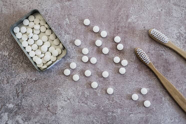 High angle close up of two wooden toothbrushes and pills in metal box. - MINF13650