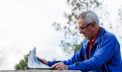 Älterer Mann liest Zeitung im Park, Seitenansicht - CAVF74691