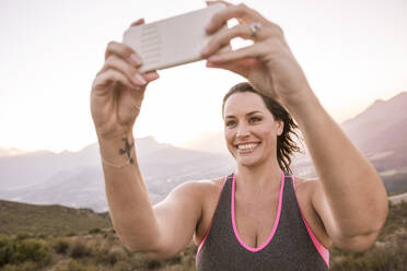 Plus-Size-Model macht Smartphone-Foto auf dem Land bei Sonnenuntergang - SDAHF00206