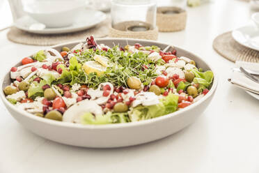 Bowl of mixed salad with pomegranate seed on laid table - SDAHF00230