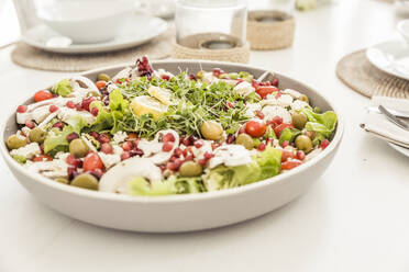 Schüssel mit gemischtem Salat mit Granatapfelkernen auf dem gedeckten Tisch - SDAHF00230
