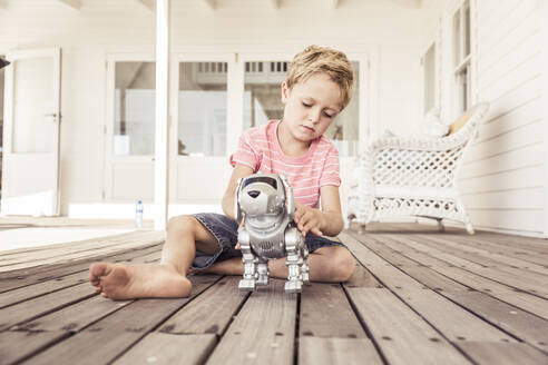 Junge spielt mit Roboterhund auf Veranda - SDAHF00237