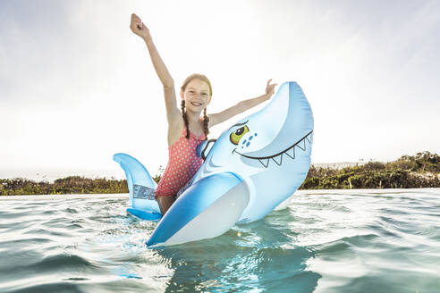 Portrait of happygirl in swimming pool with inflatable shark pool toy - SDAHF00253