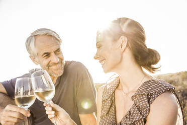 Happy couple having a glass of white wine at sunset - SDAHF00268