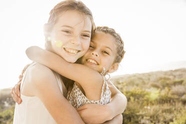 Porträt von zwei glücklichen süßen Mädchen, die sich bei Sonnenuntergang umarmen - SDAHF00272