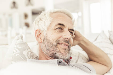 Porträt eines reifen Mannes auf der Couch im Wohnzimmer, lizenzfreies Stockfoto