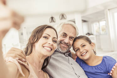 Glückliche Familie macht ein Selfie auf der Couch im Wohnzimmer - SDAHF00339