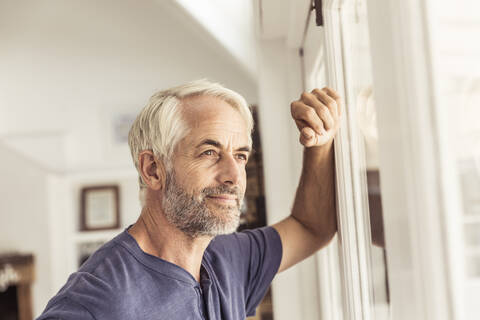 Porträt eines reifen Mannes, der aus dem Fenster schaut, lizenzfreies Stockfoto