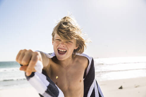 Portrait of screaming boy wrapped in a towel on the beach - SDAHF00343