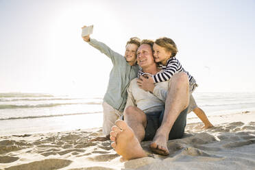 Junge mit Bruder und Vater machen ein Selfie am Strand - SDAHF00349