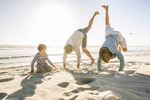 Playful father with two sons having fun on the beach stock photo