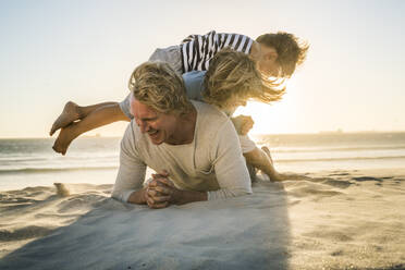 Playful father with two sons having fun on the beach - SDAHF00360